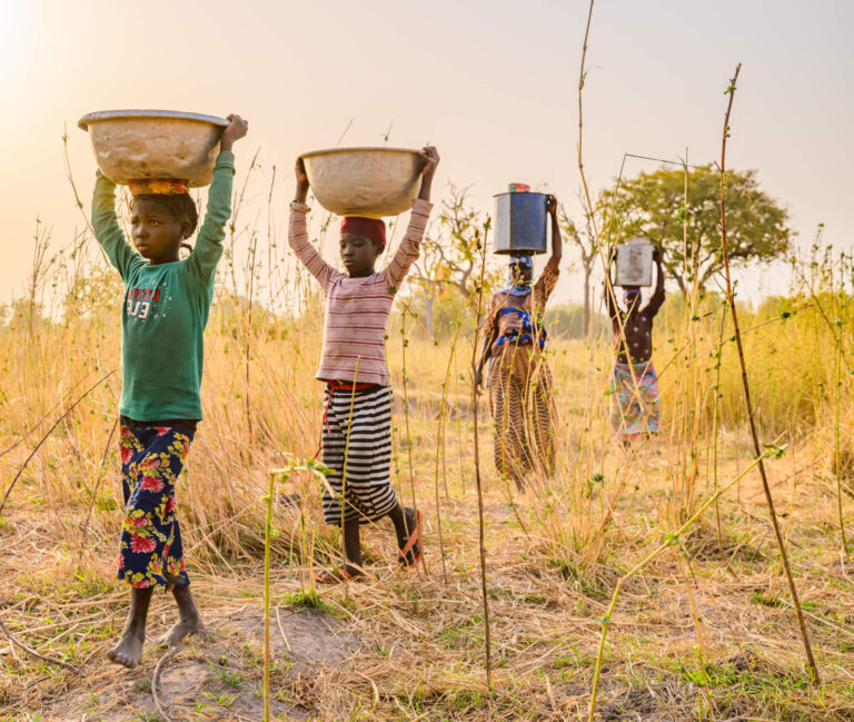 Jeune fille africaine portant un jerrican d'eau sur la tête lors de la corvée d'eau quotidienne