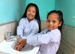 jeunes filles utilisant l'eau d'un robinet pour le lavage des main installé par world vision france